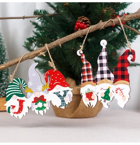 Detail of wooden gnome ornaments spelling JOY hanging on a festive Christmas pine branch