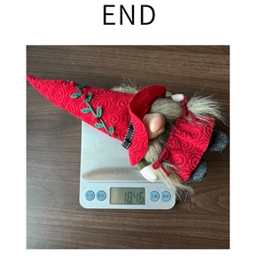 Christmas gnome plush toy weighing 184.6g on a scale over a brown wooden background