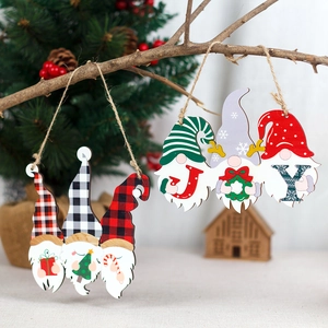 Hanging wooden Christmas gnomes with JOY letters and festive plaid hats on pine branches