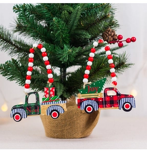 Detail of wooden truck ornaments with Noel and Joy text hanging on a Christmas tree