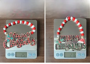 Detail showing the weight of a wooden Merry Christmas hanging sign with red plaid beads