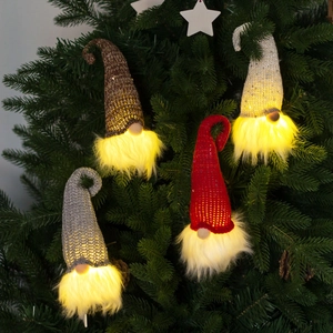 Set of four glowing Christmas gnome ornaments in red, silver, beige on pine tree