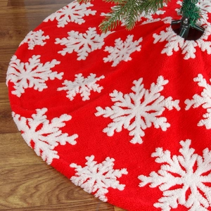 Classic red plush Christmas tree skirt with large white snowflake patterns on wood floor