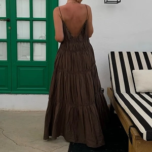 Elegant backless brown maxi dress with thin straps and layered pleats for a vacation look