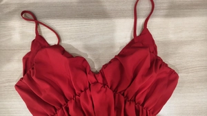 Detail of red V-neck dress featuring delicate spaghetti straps and elegant ruched bodice