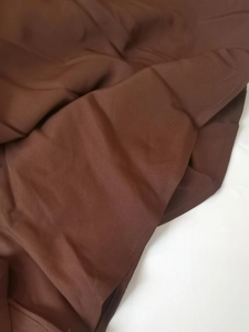 Detailed close-up of the fine stitching and smooth fabric texture on this brown dress