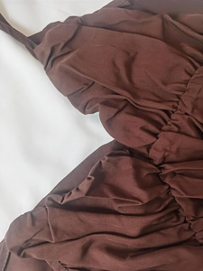 Close-up of the elegant deep brown ruched fabric detailing on this slim fit dress