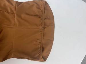 Detail view of brown PU leather jumpsuit back with invisible zipper and elastic waist