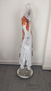 Detail view of white floral dress featuring side vertical ruffles and abstract orange print