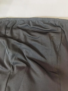Detail of black dress waist featuring elastic waistband and structured stitching on fabric