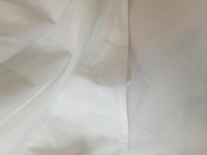 Detailed close-up showing the hem stitching and texture of white cotton fabric dress