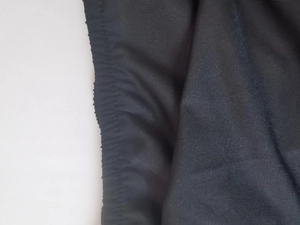 Detail of black knitted fabric texture with elastic waistband and pleat craftsmanship