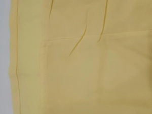Gros plan du tissu de la robe française jaune élégante avec plis fins et coutures à la taille