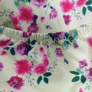 Detail of floral printed dress featuring elastic pleated waist and pink rose pattern