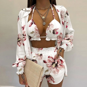 Close-up of beach three-piece set featuring artistic pink floral prints on white fabric