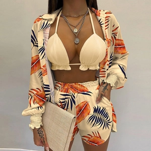Three-piece beige beach set with tropical leaf print shirt, bikini top, and shorts