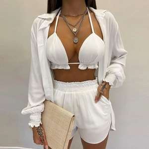 Three-piece white summer beach set with halter bikini top, high-waist shorts, and sheer cardigan