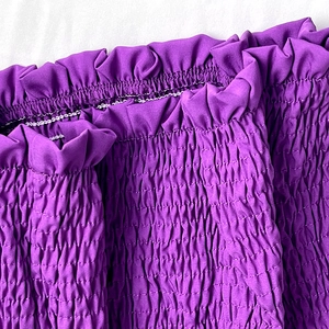 Vue détaillée du tissu élastique smocké violet avec bords volantés sur une tenue femme