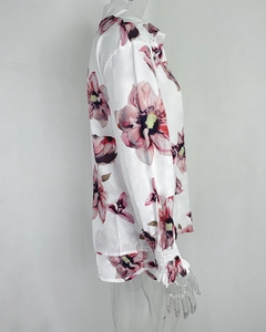 Detail of floral printed white shirt featuring ruffle cuffs and silk-like fabric texture