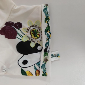 Détail de l'imprimé floral et bouton en résine sur un chemisier décontracté blanc