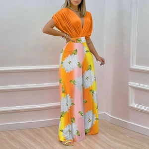 Detail view of high-waisted wide-leg pants with large white floral print and orange tones