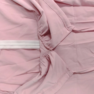 Detail of light pink dress featuring thin spaghetti straps and gathered pleats with elastic