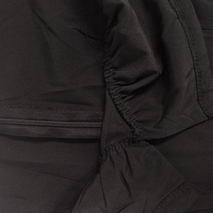 Close-up of matte black dress fabric featuring a hidden zipper and ruffled seam details
