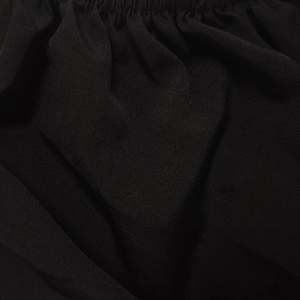 Detail of black dress featuring elasticated ruched fabric and textured woven material
