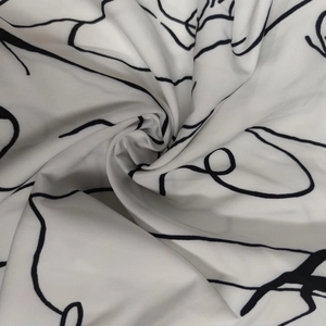 Détail du tissu blanc avec motif abstrait noir montrant la texture douce et le drapé