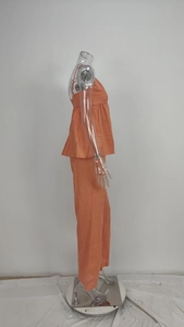 Dettaglio del top arancione senza maniche con peplo e pantaloni dritti coordinati in cotone