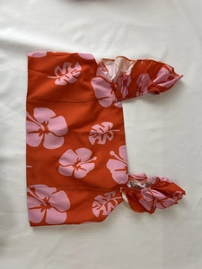 Detail of summer orange top with pink hibiscus print and elastic ruffled cuffs