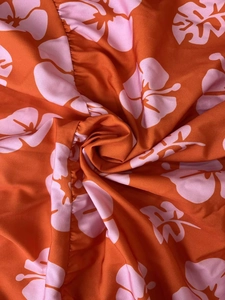 Detailed view of lightweight orange fabric with pink hibiscus floral print for summer dress