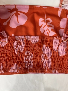 Detail of tropical floral print dress featuring elastic smocking and orange hibiscus pattern