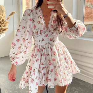 Close-up of white floral mini dress with lace V-neckline and pink rose pattern detail