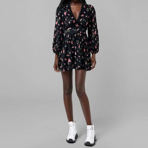 Détail du col en V et de l'imprimé floral rose sur une robe noire cintrée