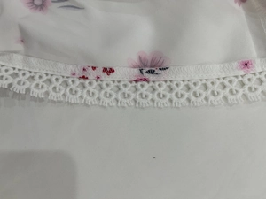 Détail de l'imprimé floral rose sur tissu blanc avec bordure en dentelle blanche crochetée