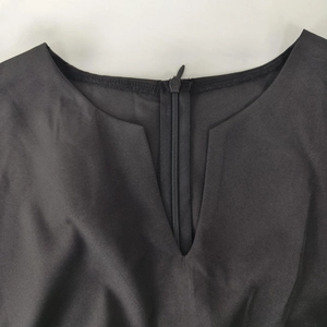 Detail view of the V-neckline with a hidden zipper on a black wide-leg jumpsuit