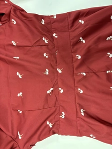 Détail du tissu de robe bordeaux à fleurs montrant les coutures et l'imprimé floral