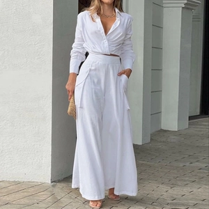 Outdoor shot of white two-piece set with V-neck cropped shirt and wide-leg trousers