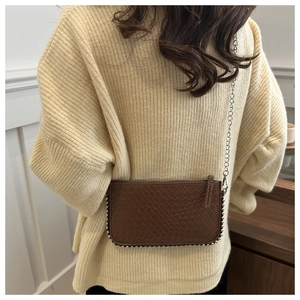 Detailed view of brown woven texture handbag with metallic ball chain trim and silver strap