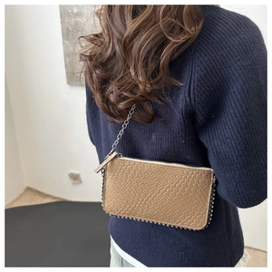 Detail of khaki faux crocodile texture crossbody bag with silver rivet studs and chain strap