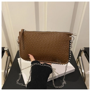 Detail of brown crocodile pattern shoulder bag with silver bead trim and chain strap