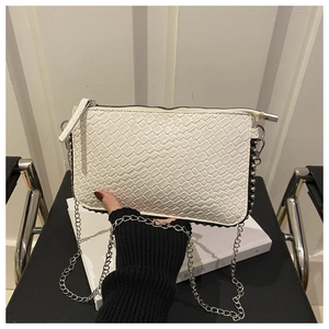Detail shot of white woven texture envelope bag with silver chain and metal bead accents