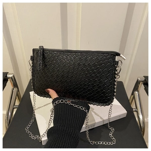 Detail of black woven crossbody bag featuring silver stud trim and metal chain strap