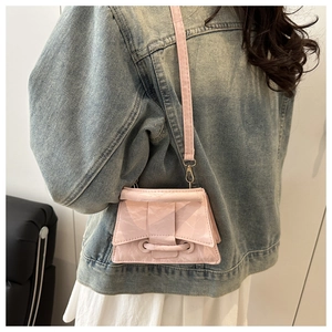Detail of pink crossbody bag featuring pleated texture and unique ribbon knot decoration