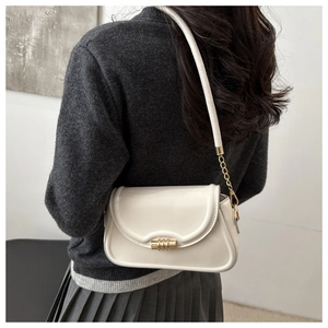 Detail of a creamy white glossy underarm bag featuring a gold clasp and chain strap