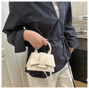 Detail showing white mini handbag texture with single handle and buckle strap closure