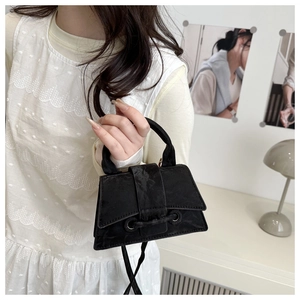 Detail of vintage black mini handbag with pleated texture and drawstring buckle design