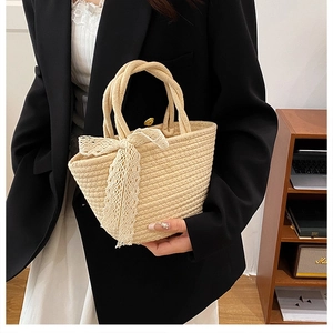 Detail of hand-woven straw tote bag with elegant white lace bow and dual handles