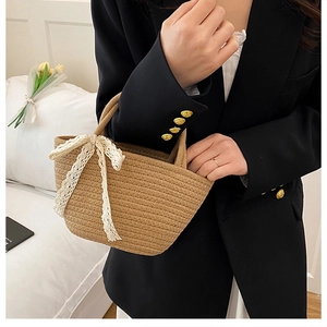 Detail of handmade straw woven handbag with white lace bow on the front panel